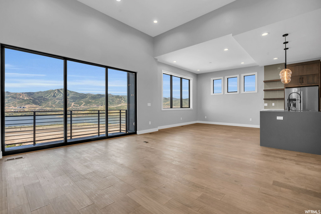 Unfurnished living room featuring light hardwood / wood-style flooring and a water and mountain view