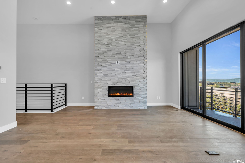 Unfurnished living room featuring light wood-type flooring and a stone fireplace