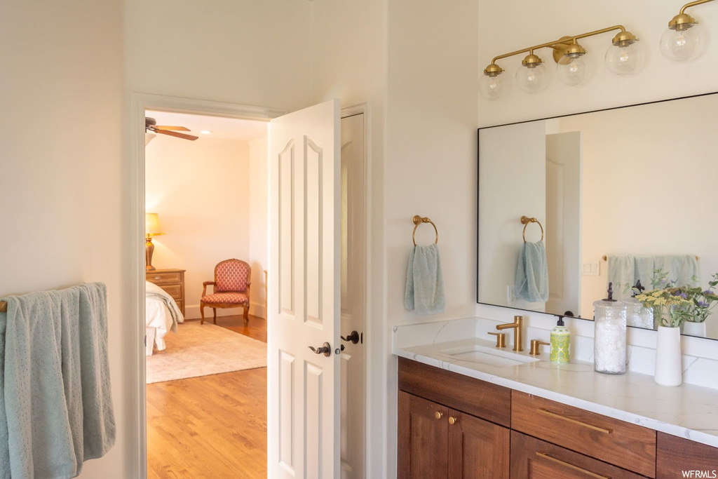 Bathroom with mirror, vanity, and light hardwood flooring