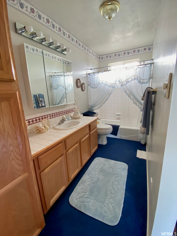 Full bathroom featuring toilet, shower / tub combo with curtain, and vanity
