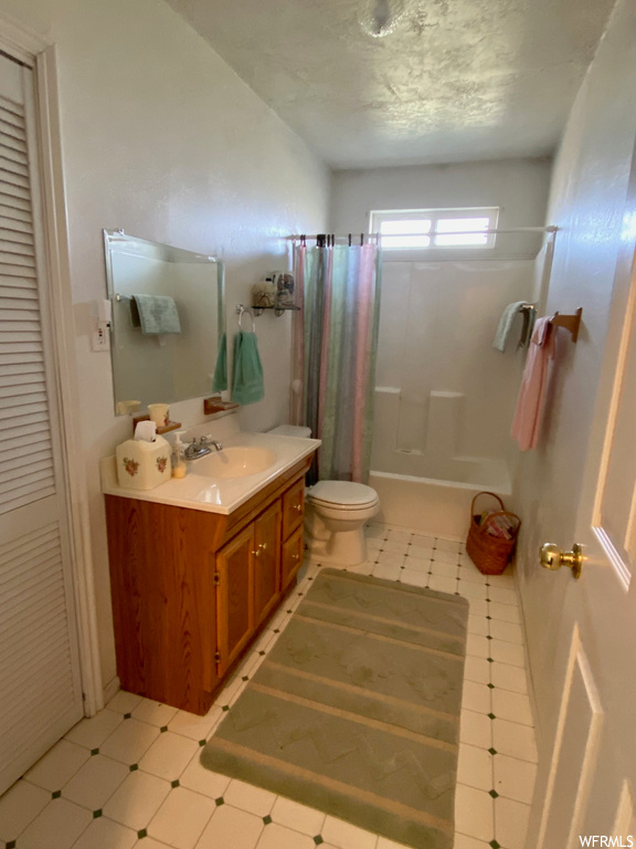 Bathroom with toilet, tile flooring, and vanity with extensive cabinet space