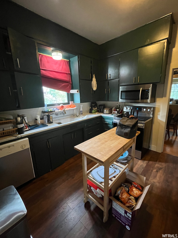 Kitchen featuring dark hardwood flooring, stainless steel appliances, light countertops, and dark brown cabinets