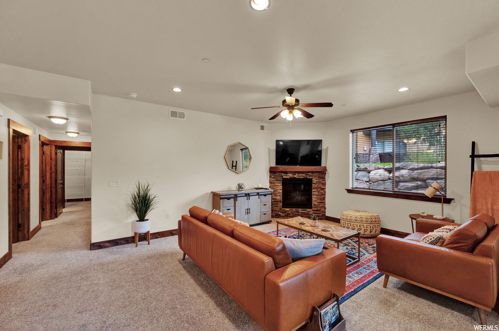 Carpeted living room featuring ceiling fan and a fireplace