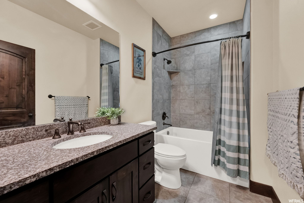 Full bathroom featuring mirror, large vanity, light tile flooring, and shower / bathtub combination with curtain