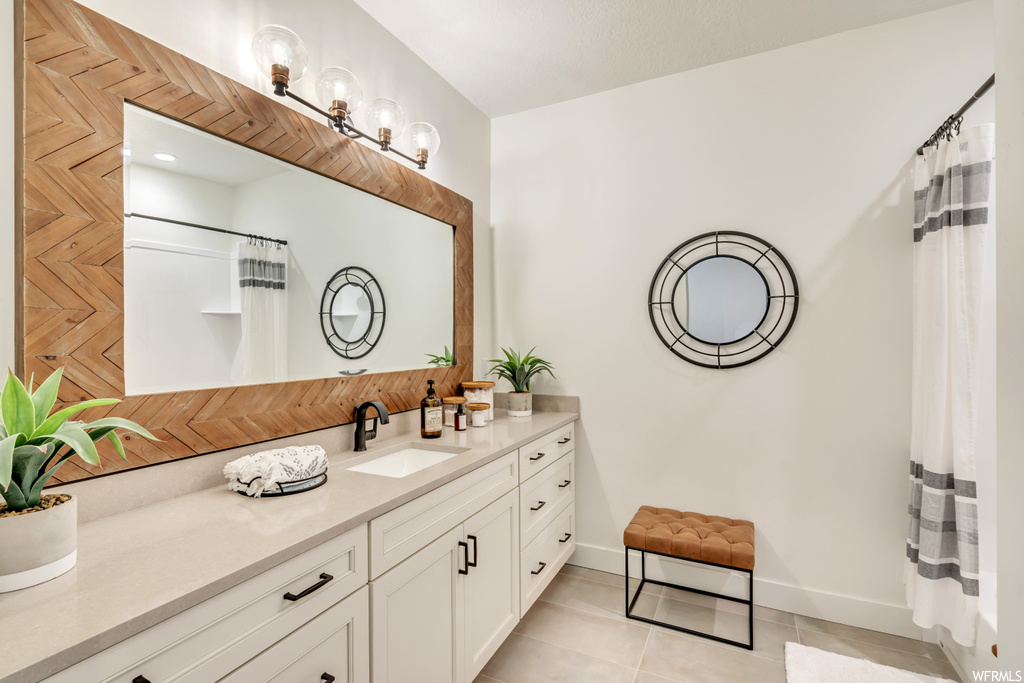 Bathroom with light tile floors, oversized vanity, and mirror
