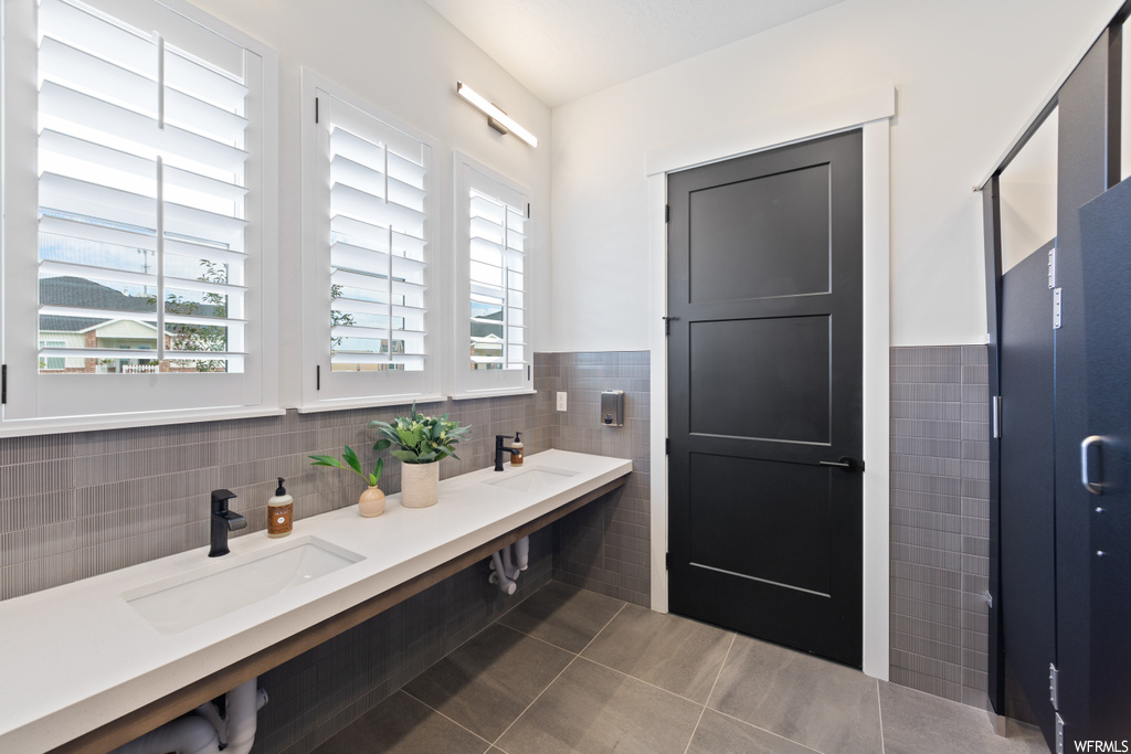 Bathroom with tile walls, tile floors, vanity, backsplash, and mirror