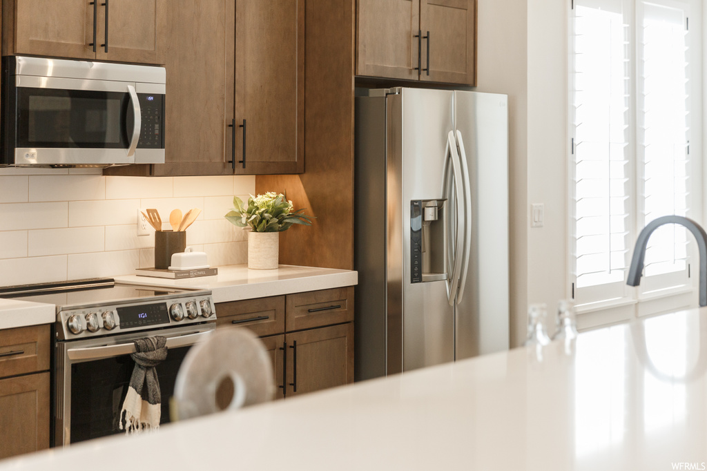 Kitchen featuring light countertops, appliances with stainless steel finishes, and backsplash