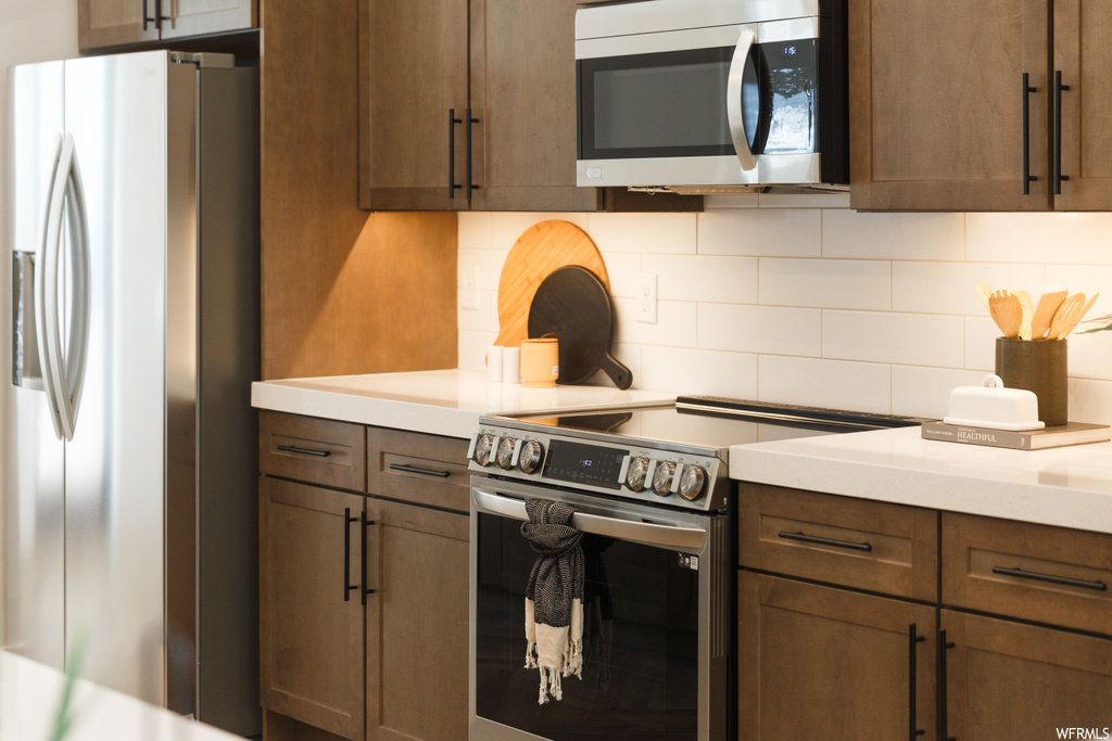 Kitchen featuring appliances with stainless steel finishes, backsplash, and light countertops