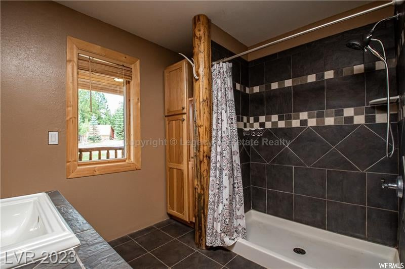 Bathroom featuring curtained shower, sink, and tile flooring