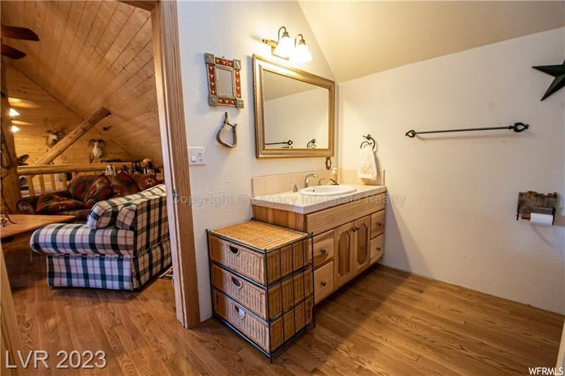 Bathroom featuring light hardwood floors, mirror, vanity, lofted ceiling, and wooden ceiling