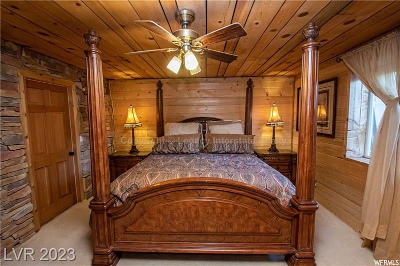 Bedroom featuring wood walls, ceiling fan, light carpet, and wood ceiling