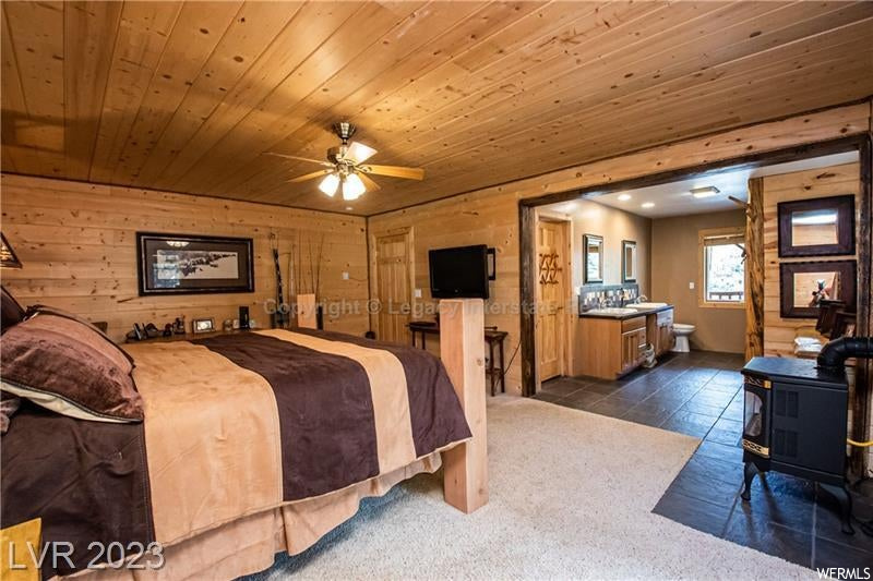 Carpeted bedroom with ceiling fan, wooden walls, and wooden ceiling