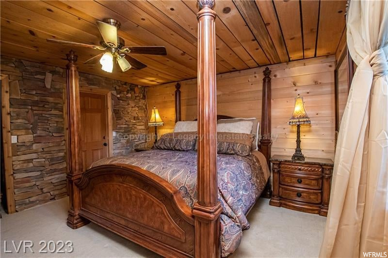 Carpeted bedroom with wood walls and wood ceiling