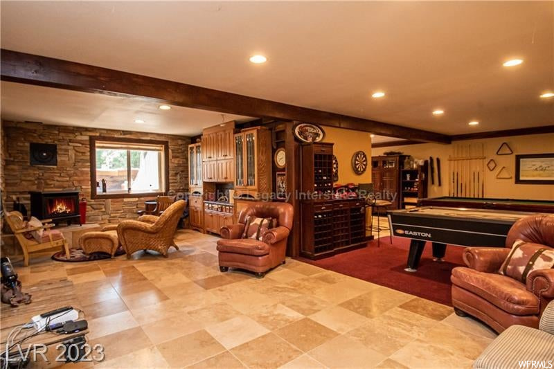 Game room featuring light tile flooring, a fireplace, and beamed ceiling