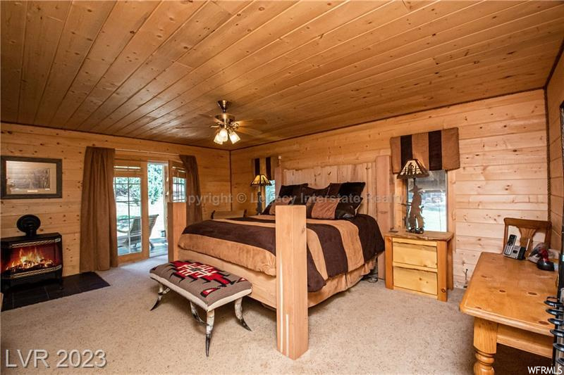 Carpeted bedroom with wooden walls and wooden ceiling