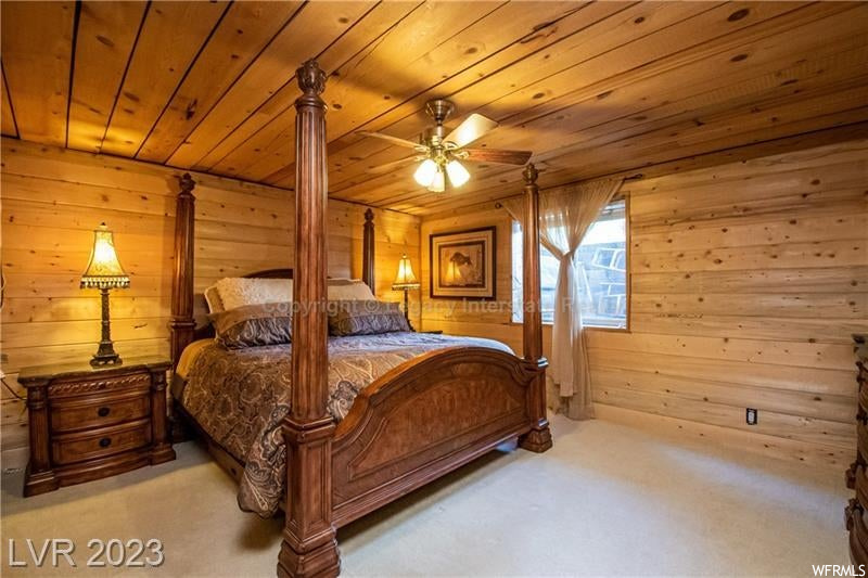 Carpeted bedroom with wood walls, ceiling fan, and wood ceiling