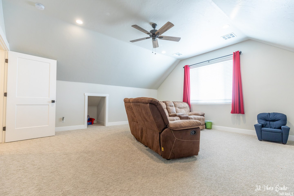 Living room featuring vaulted ceiling, light carpet, and ceiling fan