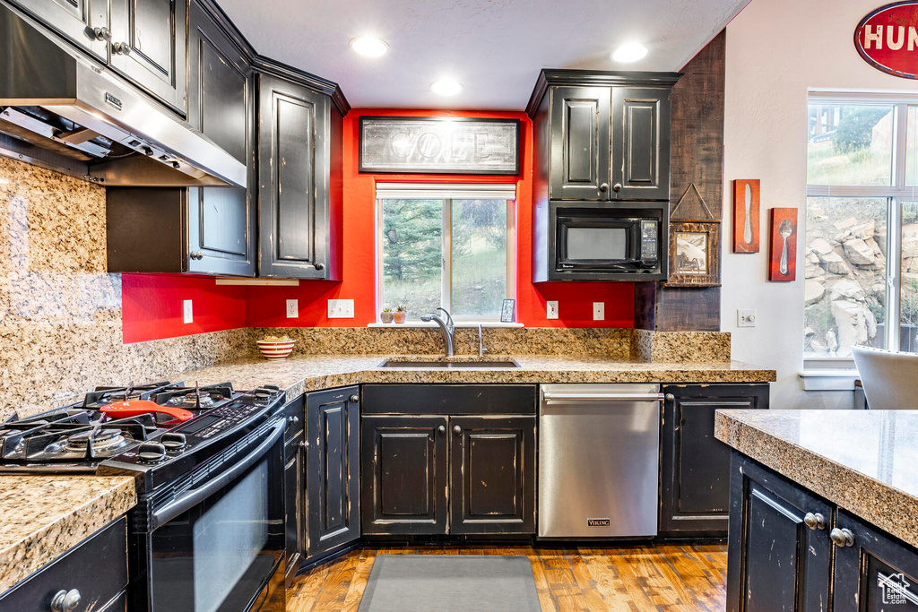 Kitchen with sink, light hardwood / wood-style floors, backsplash, and black appliances
