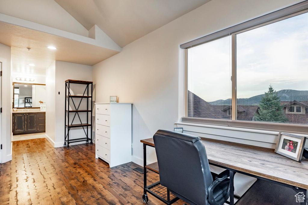 Office with a mountain view, lofted ceiling, dark wood-type flooring, and a healthy amount of sunlight