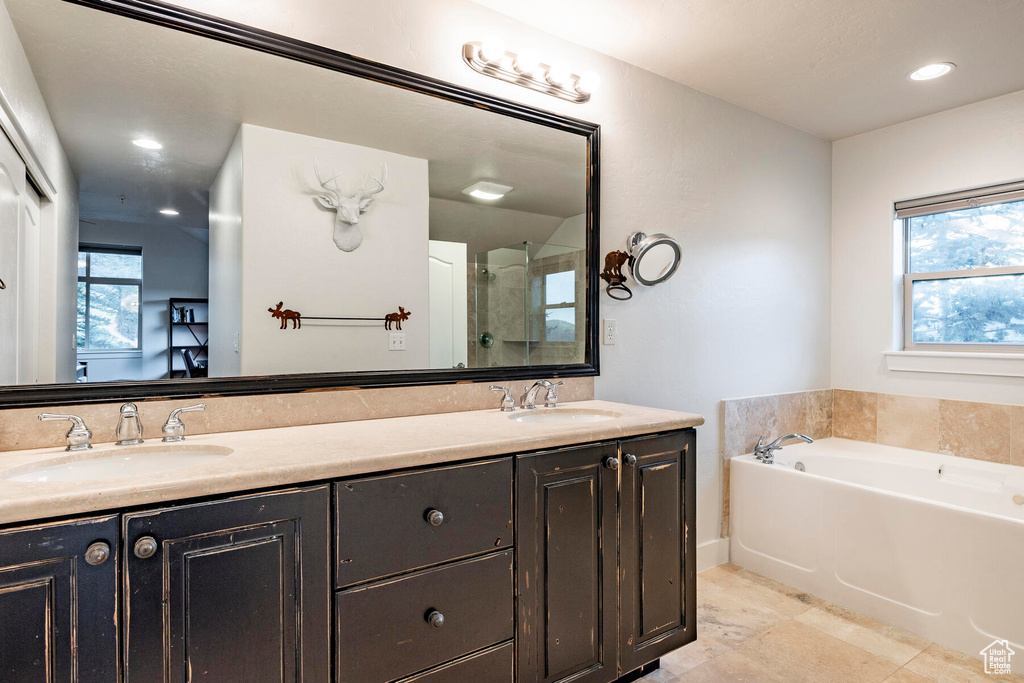 Bathroom featuring dual sinks, tile floors, oversized vanity, and plus walk in shower