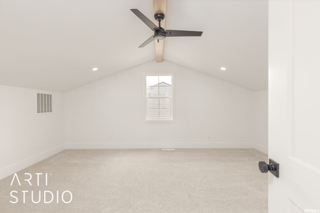 Additional living space with vaulted ceiling, light carpet, and ceiling fan