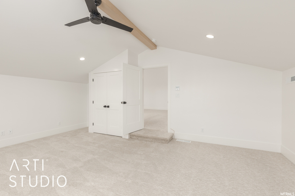 Additional living space featuring lofted ceiling with beams, light carpet, and ceiling fan