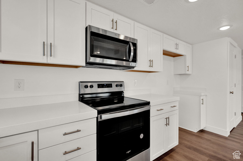 Kitchen featuring white cabinetry, dark wood-type flooring, and stainless steel appliances