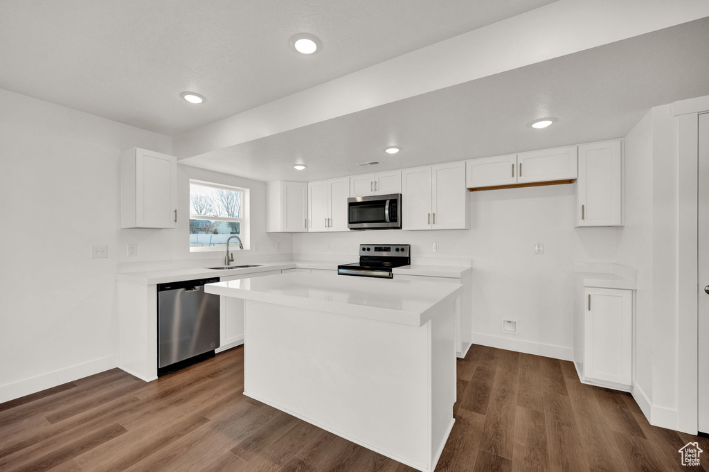 Kitchen featuring white cabinetry, dark hardwood / wood-style flooring, appliances with stainless steel finishes, and a kitchen island