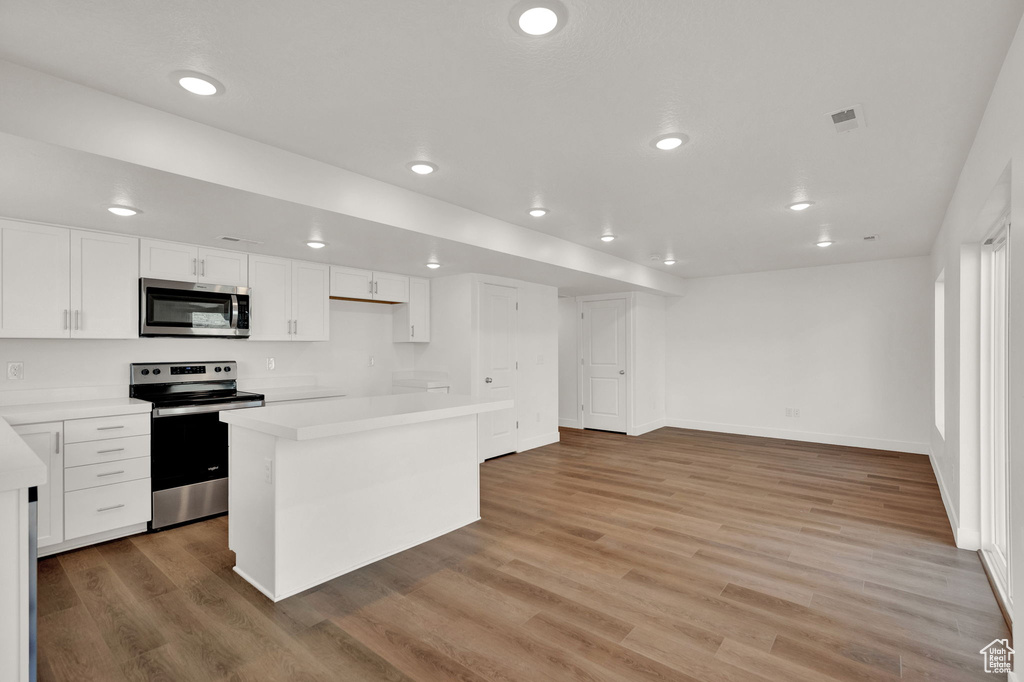 Kitchen featuring a kitchen island, light hardwood / wood-style flooring, stainless steel appliances, and white cabinets