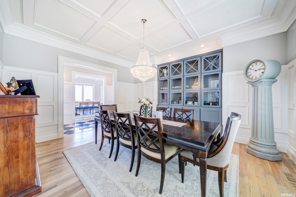 Wood floored dining room featuring ornamental molding and coffered ceiling