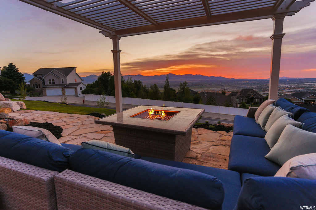 Patio terrace at dusk with a mountain view, an outdoor living space with a fire pit, and a pergola