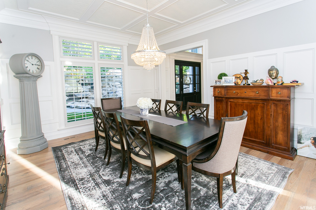 Dining room with coffered ceiling, light hardwood floors, and a chandelier