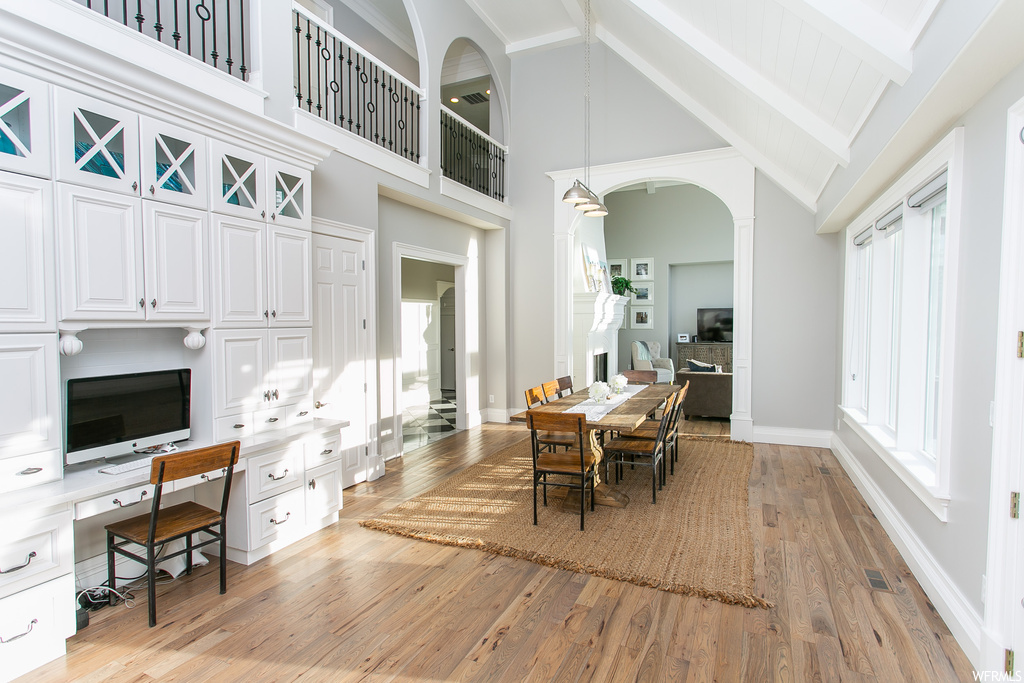 Hardwood floored dining room with a high ceiling, vaulted ceiling with beams, and a wealth of natural light