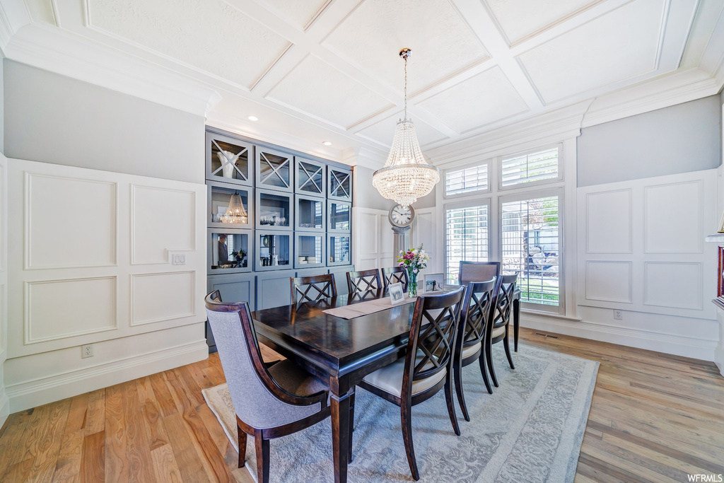 Dining room with crown molding, coffered ceiling, and light parquet floors