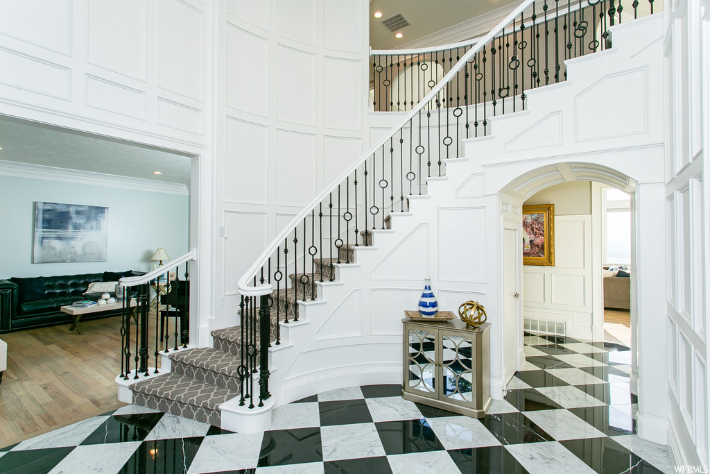 Stairs featuring a high ceiling, light tile floors, and crown molding
