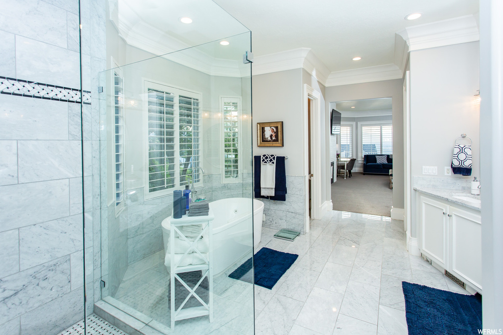 Bathroom with independent shower and bath, light tile flooring, crown molding, and vanity