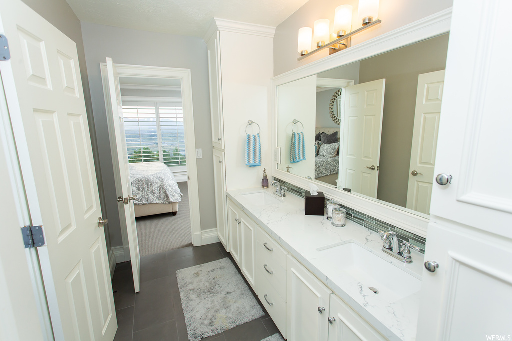 Bathroom with double sink vanity, mirror, and tile floors
