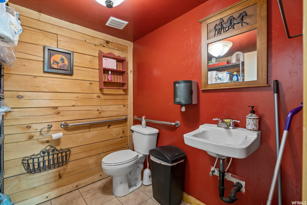 Bathroom featuring washbasin, light tile flooring, and mirror
