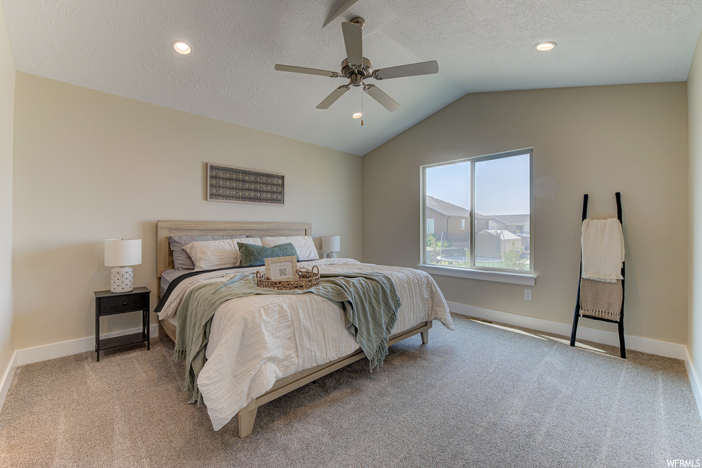 Carpeted bedroom featuring ceiling fan, vaulted ceiling, and a textured ceiling