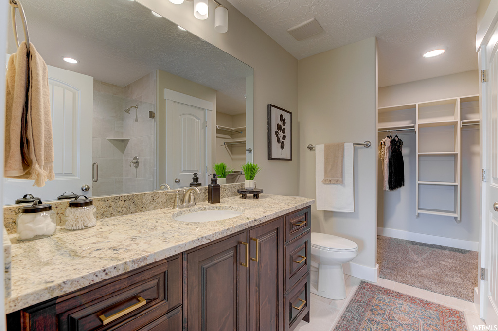 Bathroom featuring vanity, a textured ceiling, tile flooring, mirror, and a tile shower
