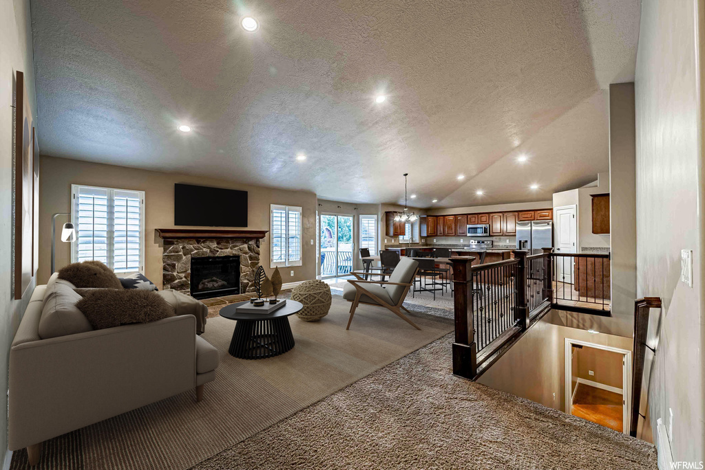 Carpeted living room with lofted ceiling, a fireplace, and a textured ceiling