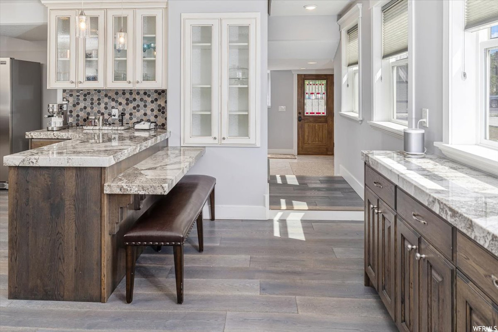 Kitchen featuring light hardwood floors, backsplash, stainless steel refrigerator, and light countertops