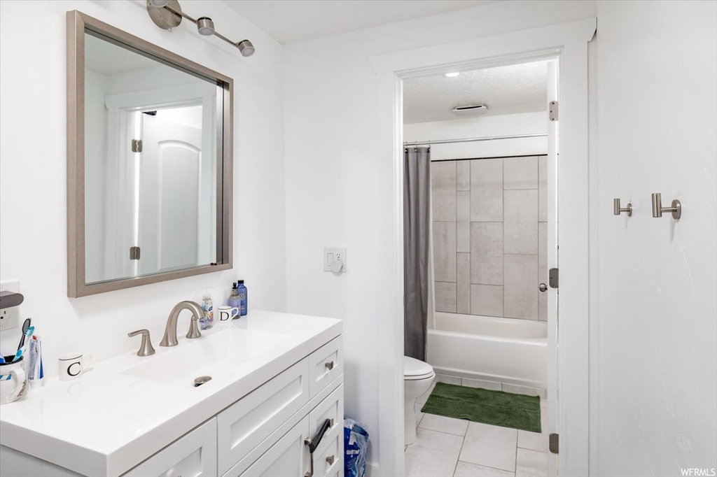 Full bathroom with oversized vanity, mirror, light tile floors, and shower / tub combo