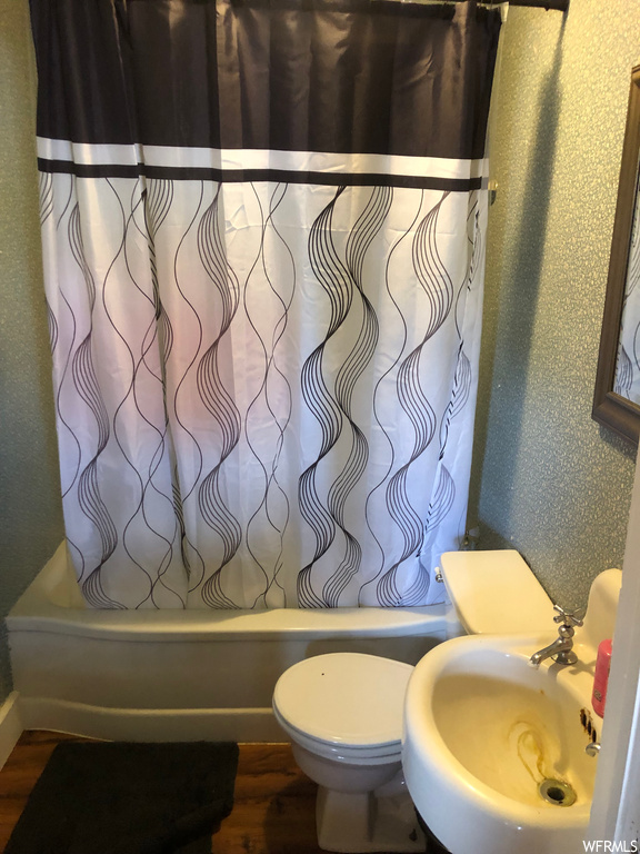 Bathroom with washbasin, shower / bath combo, and hardwood flooring