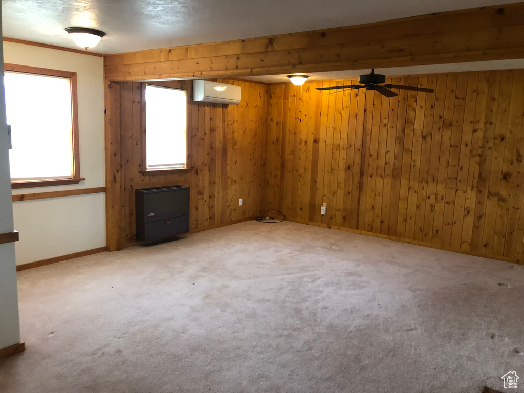 Basement featuring plenty of natural light, carpet, ceiling fan, and a wall mounted air conditioner