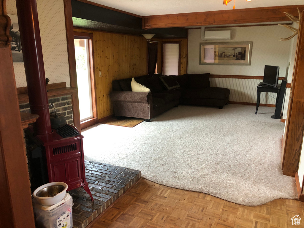 Carpeted living room featuring a wood stove and a wall unit AC