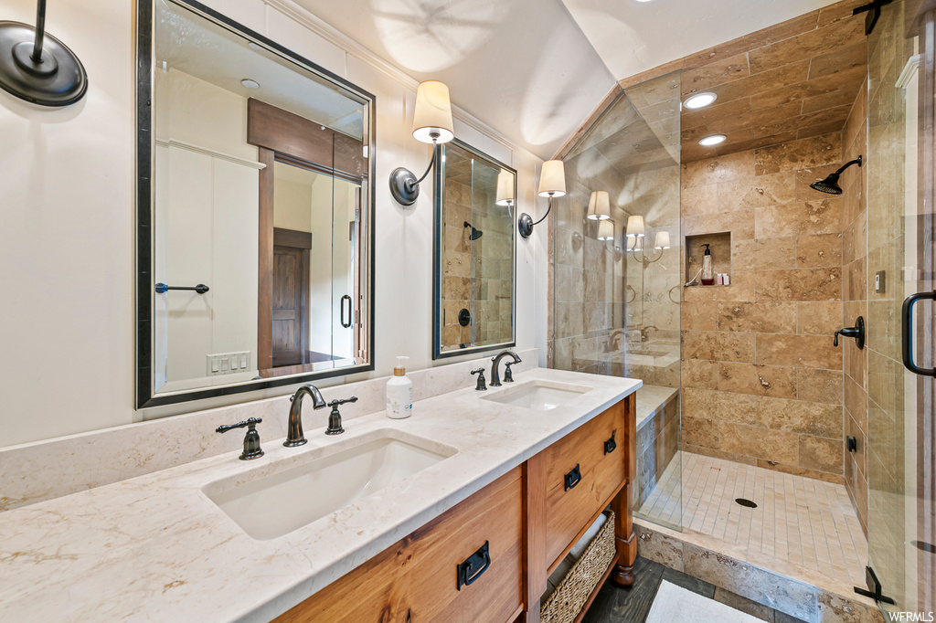 Bathroom with mirror, an enclosed shower, and dual vanity