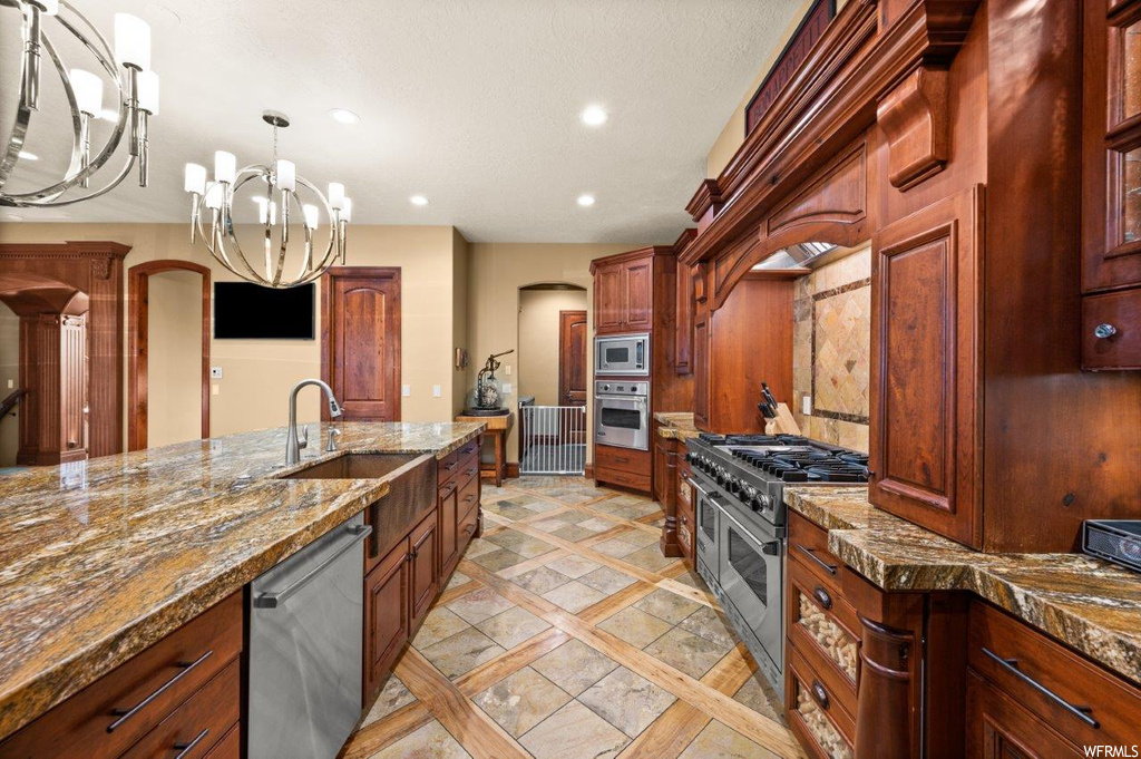 Kitchen with appliances with stainless steel finishes, stone counters, and light tile floors