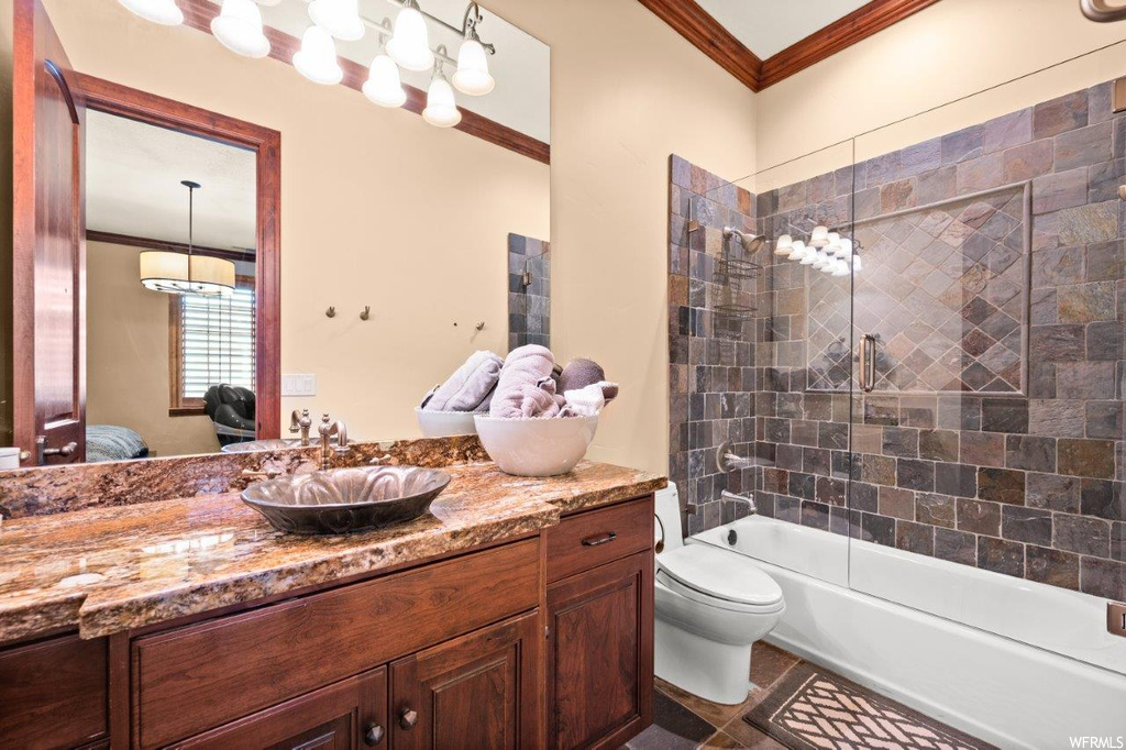 Full bathroom with shower / bath combination with glass door, ornamental molding, tile floors, vanity, and mirror