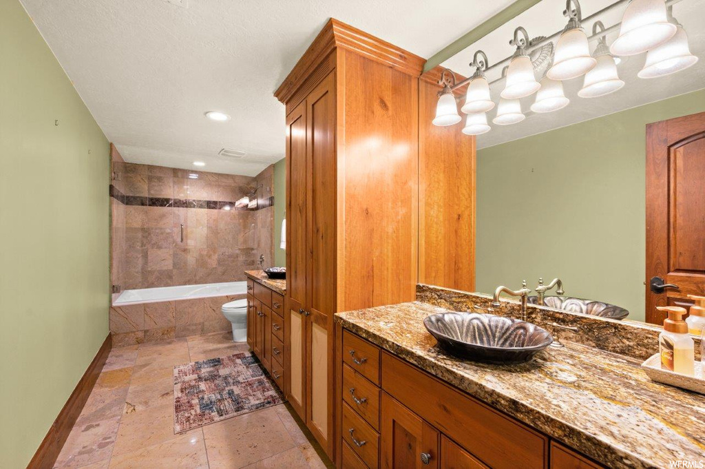 Full bathroom with light tile flooring, mirror, tiled shower / bath, and vanity